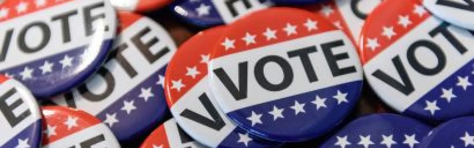A pile of pinback buttons with the word Vote displayed across their front.
