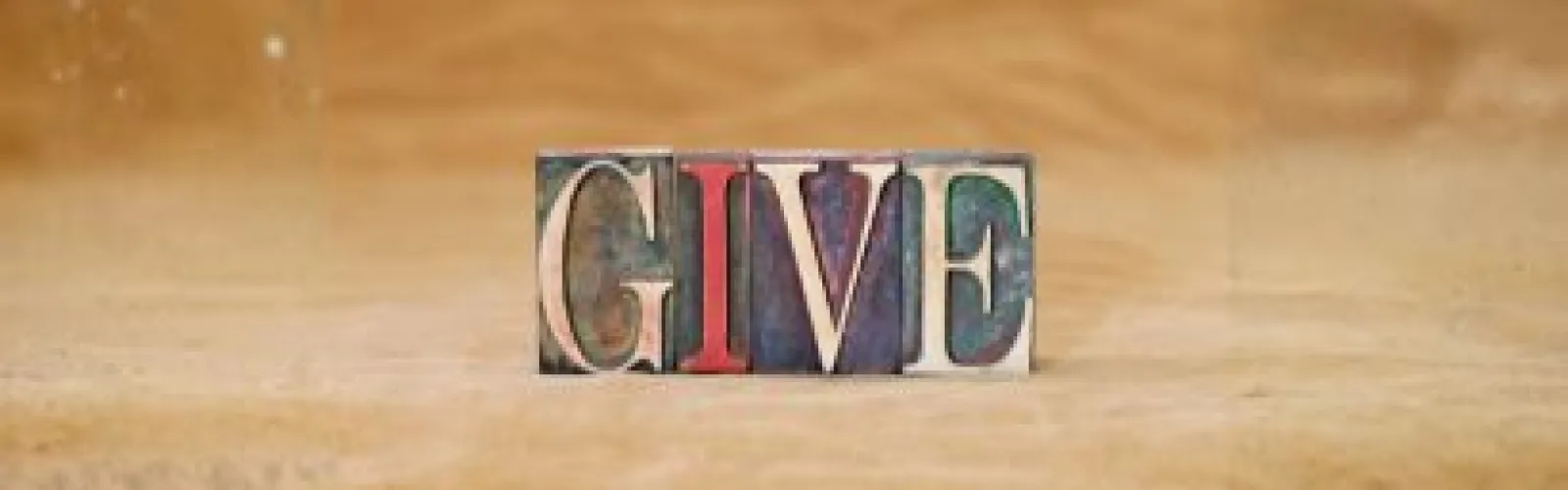 The word give is spelled out in stamps on a tan background.